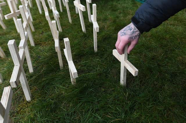 A man leaves a cross in memory of a victim of drus at Springburn Parish Church in Glasgow (Picture: John Devlin)