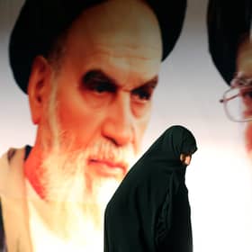 An Iranian woman walks past a giant poster showing Iran's supreme leader, Ayatollah Ali Khamenei, right, and the founder of the Islamic republic, Ayatollah Ruhollah Khomeini (Picture: Atta Kenare/AFP via Getty Images)