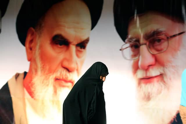 An Iranian woman walks past a giant poster showing Iran's supreme leader, Ayatollah Ali Khamenei, right, and the founder of the Islamic republic, Ayatollah Ruhollah Khomeini (Picture: Atta Kenare/AFP via Getty Images)