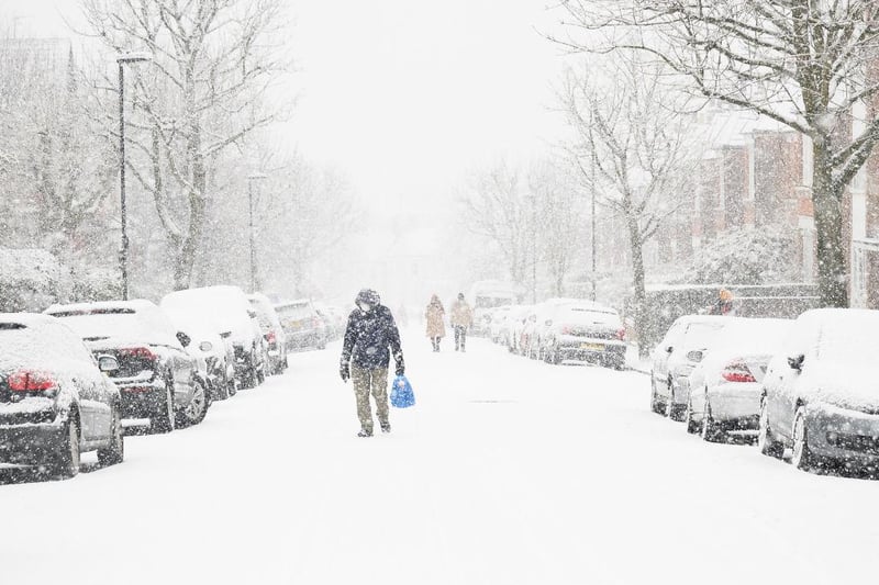 A man in a facemask walking through Muswell Hill, London, can barely be seen due to the heavy snow.