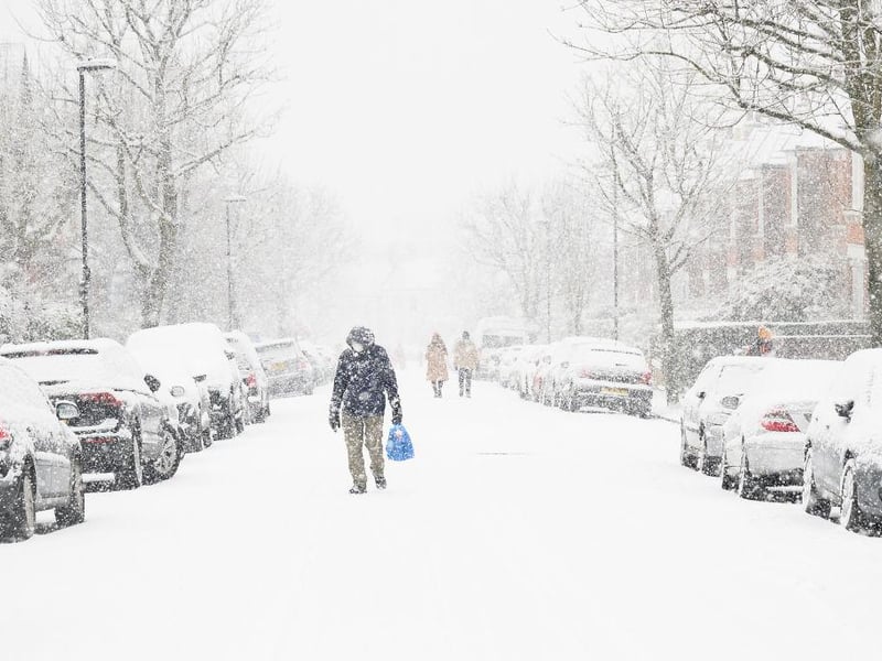 A man in a facemask walking through Muswell Hill, London, can barely be seen due to the heavy snow.
