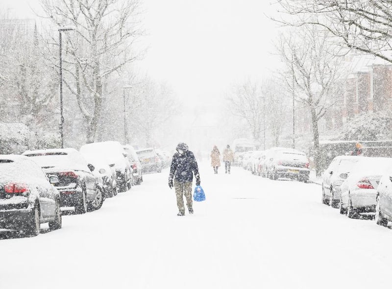 A man in a facemask walking through Muswell Hill, London, can barely be seen due to the heavy snow.
