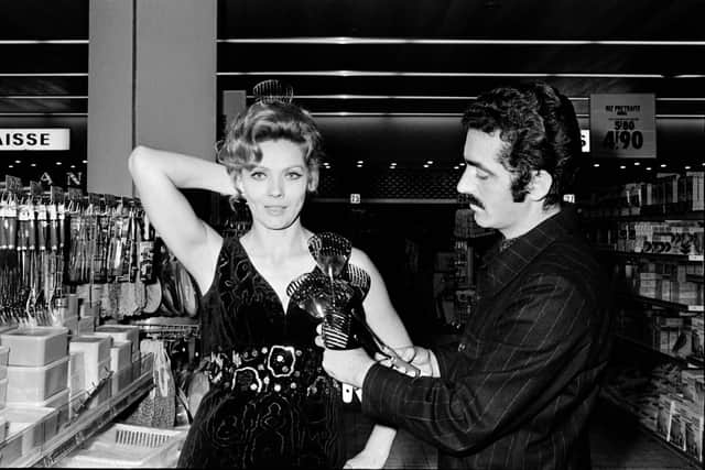 Spanish fashion designer Paco Rabanne tries a creation with cutleries on French actress Corinne Marchand during the Home economics (or domestic science) exhibition at the shopping mall of Saint-Laurent-du-Var.