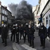 French French Republican Security Corps (CRS - Compagnies Republicaines de Securite) police officers in riot gear operate during a demonstration, with a smoke rising in the background, a week after the government pushed a pensions reform through parliament without a vote, using the article 49.3 of the constitution. (Photo by PHILIPPE LOPEZ/AFP via Getty Images)