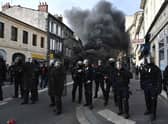 French French Republican Security Corps (CRS - Compagnies Republicaines de Securite) police officers in riot gear operate during a demonstration, with a smoke rising in the background, a week after the government pushed a pensions reform through parliament without a vote, using the article 49.3 of the constitution. (Photo by PHILIPPE LOPEZ/AFP via Getty Images)