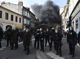 French French Republican Security Corps (CRS - Compagnies Republicaines de Securite) police officers in riot gear operate during a demonstration, with a smoke rising in the background, a week after the government pushed a pensions reform through parliament without a vote, using the article 49.3 of the constitution. (Photo by PHILIPPE LOPEZ/AFP via Getty Images)