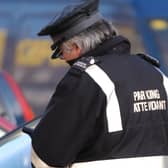 Parking attendant in Edinburgh writing a parking ticket