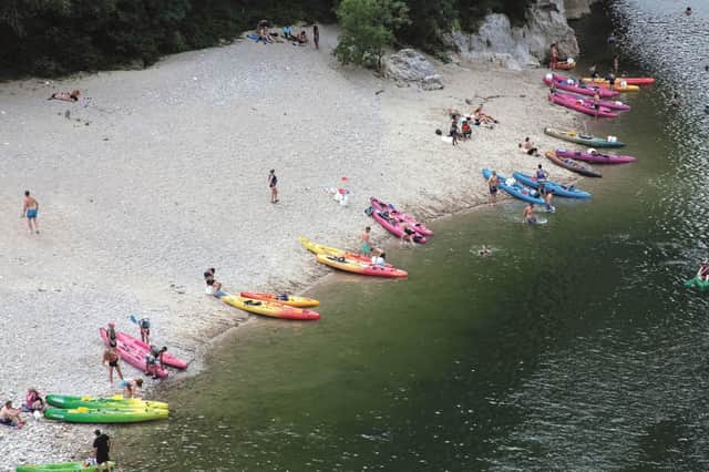 Kayakers and swimmers take a rest from the rapids on the banks of the river.