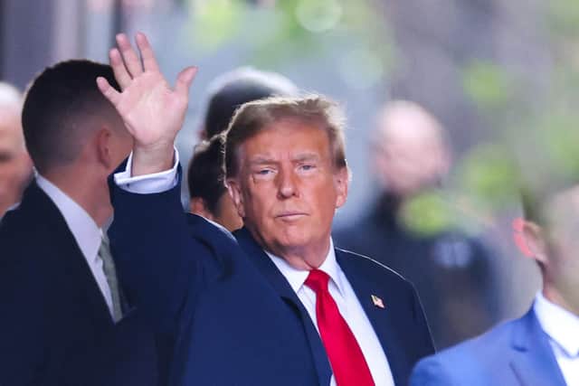 Former US President Donald Trump waves as he departs Trump Tower for Manhattan Criminal Court