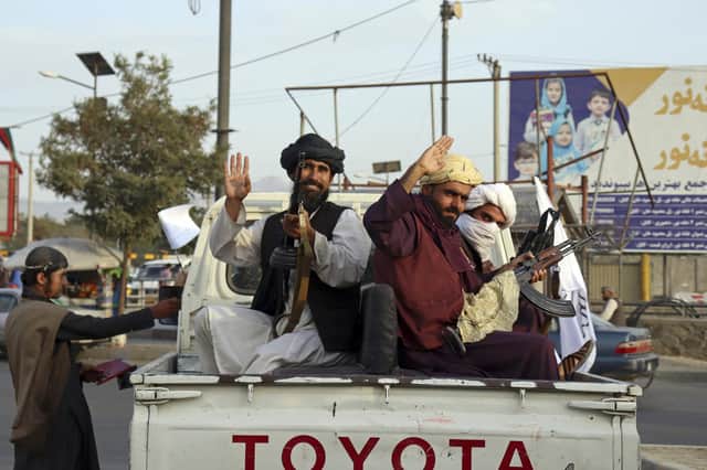 Taliban fighters wave from the back of a pickup truck, in Kabul, Afghanistan, Monday, August 30