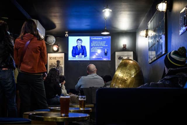 Clients watch French President Emmanuel Macron's evening televised address to the nation in a cafe in Bordeaux, southern France. (Photo by Philippe LOPEZ / AFP)