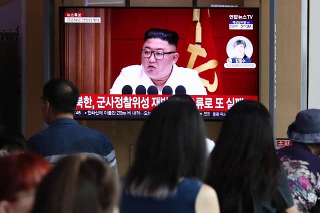 People watch a television broadcast showing a file image of North Korean leader Kim Jong-Un at his government's attempt to launch a spy satellite last month.