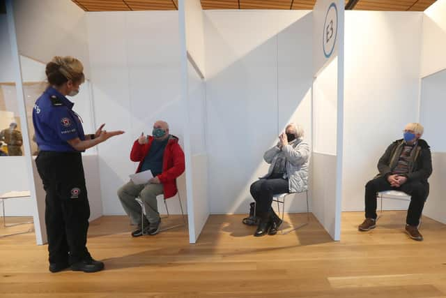 A St Andrews First Aider chats with (left to right) James Logan, Sylvia Campbell and Michael Maddocks as they sit in a waiting area after receiving an injection of a coronavirus vaccine from the millitary who are assisting with the vaccination programme at the Royal Highland Showground near Edinburgh. Picture date: Thursday February 4, 2021.