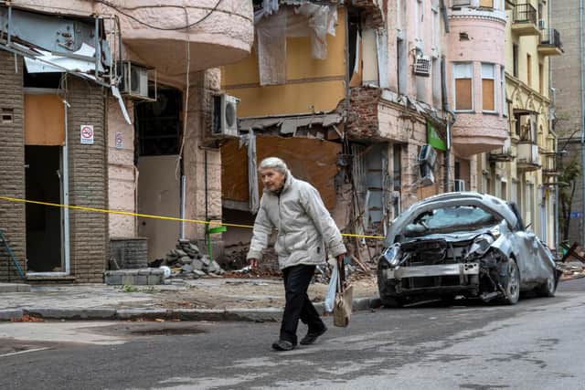An elderly woman walks past a building partially destroyed by a missile strike in the centre of Kharkiv, on September 13, 2022, amid the Russian invasion of Ukraine. (Photo by SERGEY BOBOK / AFP) (Photo by SERGEY BOBOK/AFP via Getty Images)