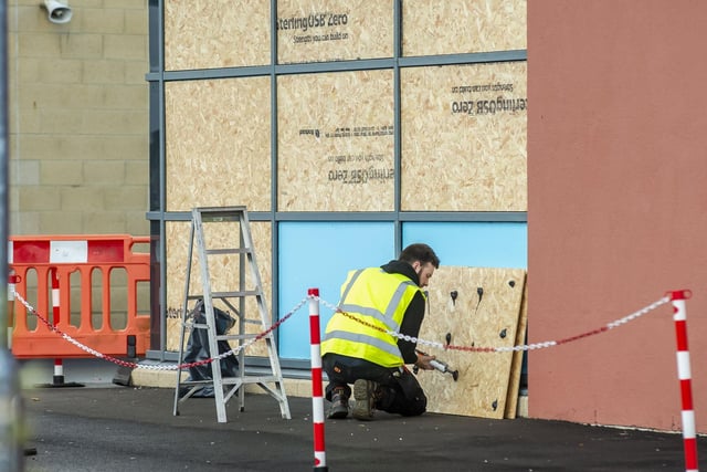 A worker boards up a school after damage by youths who smashed windows in a night of carnage.