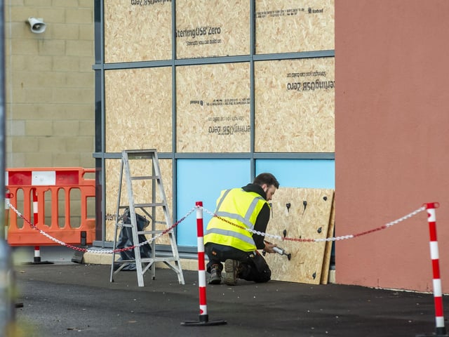 A worker boards up a school after damage by youths who smashed windows in a night of carnage.