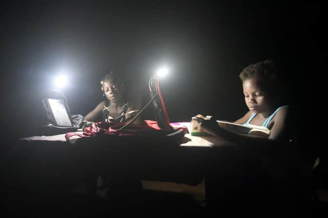 Two girls study next to lamps powered by energy from solar panels in the southeastern Rubino district of Côte d'Ivoire (Picture: Sia Kambou/AFP via Getty Images)