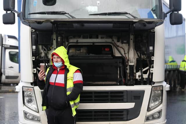 A driver takes shelter from the rain beneath the bonnet of his lorry outside the Port of Dover.