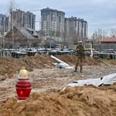 A Ukrainian serviceman stands guard near a mass grave in Bucha, near Kyiv on Saturday.