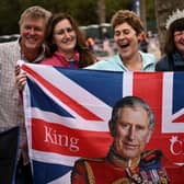 Royal fans pose with a Union flag incorporating King Charles III along the Coronation procession route in London this weekend (Picture:  Marco Bertorello/AFP)