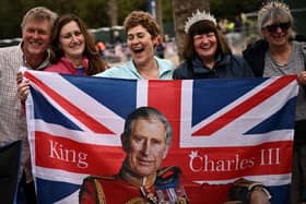 Royal fans pose with a Union flag incorporating King Charles III along the Coronation procession route in London this weekend (Picture:  Marco Bertorello/AFP)
