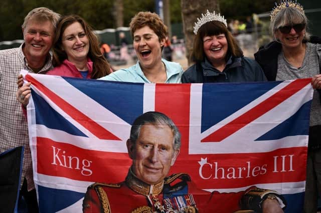 Royal fans pose with a Union flag incorporating King Charles III along the Coronation procession route in London this weekend (Picture: Marco Bertorello/AFP)