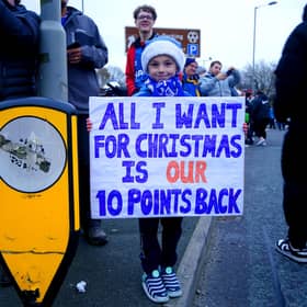 An Everton fan holds up a sign in protest of the club's point deduction.