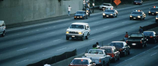 Motorists stop and wave as police cars pursue a white Ford Bronco, driven by Al Cowlings, carrying fugitive murder suspect OJ Simpson, during a 90-minute, slow-speed car chase in Los Angeles in 1994 (Picture: Jean-Marc Giboux/Liaison/Getty Images)
