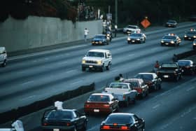 Motorists stop and wave as police cars pursue a white Ford Bronco, driven by Al Cowlings, carrying fugitive murder suspect OJ Simpson, during a 90-minute, slow-speed car chase in Los Angeles in 1994 (Picture: Jean-Marc Giboux/Liaison/Getty Images)