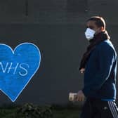 A man in a face mask walks past graffiti in support of the NHS in East London