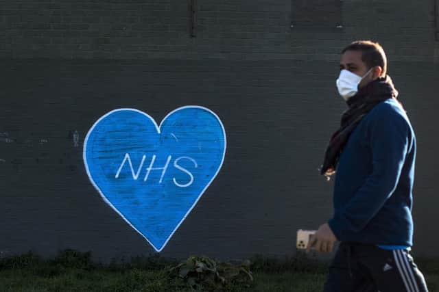 A man in a face mask walks past graffiti in support of the NHS in East London