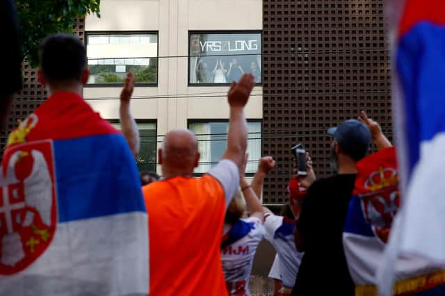 People look on from a government detention centre as supporters of Serbia's Novak Djokovic gather outside the facility where the tennis champion is reported to be staying in Melbourne. (Photo by CON CHRONIS/AFP via Getty Images)