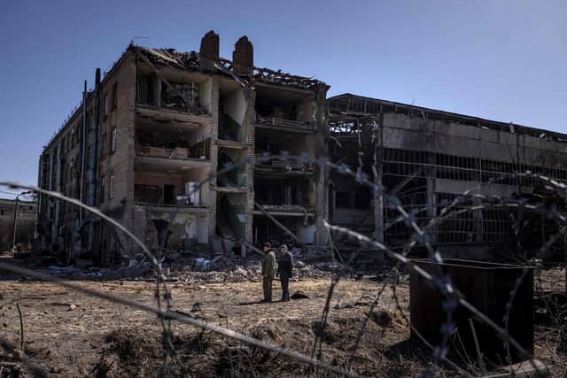 TOPSHOT - People stand beside damaged buildings  at the Vizar company military-industrial complex, after the site was hit by overnight Russian strikes, in the town of Vyshneve, southwestern suburbs of Kyiv, on April 15, 2022. - A day after Moscow suffered a stinging symbolic defeat with the loss of its Black Sea fleet flagship, Russia’s Defence Ministry promised to ramp up missile attacks on the Ukrainian capital in response to Ukraine’s alleged military “diversions on the Russian territory.”