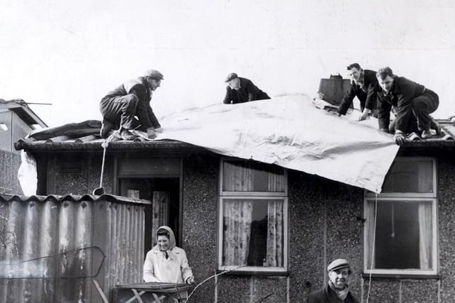 Residents of Skye Edge Avenue get a roof over their heads as workmen lay tarpaulin to protect their hurricane-ravaged homes on February 17, 1962. A disaster zone was declared as freak winds killed three people in Sheffield and one in Barnsley, left 250 people homeless and 70,000 homes damaged. An appeal fund was launched by the lord mayor to help those affected