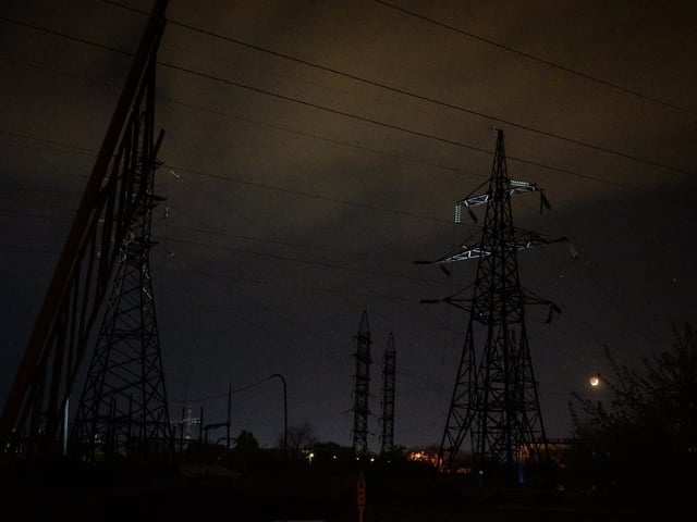 An electricity pylon is illuminated by torchlight as police and engineers inspect the area following explosions after a Russian missile strike on May 3, 2022 in Lviv, Ukraine. Photo by Leon Neal/Getty Images) (Photo by Leon Neal/Getty Images