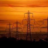 A line of pylons silhouetted against a fiery sky on a cold winters evening over Leeds