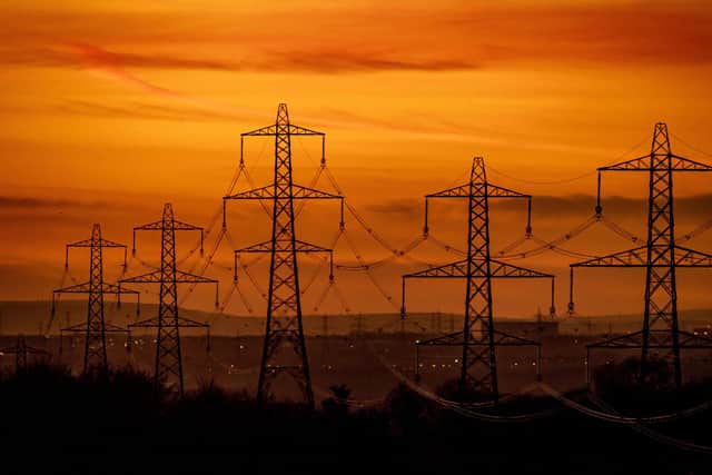 A line of pylons silhouetted against a fiery sky on a cold winters evening over Leeds