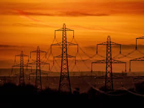A line of pylons silhouetted against a fiery sky on a cold winters evening over Leeds
