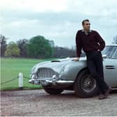 Edinburgh-born actor Sean Connery poses beside the Aston Martin DB5 in a publicity shot for the James Bond film Goldfinger.