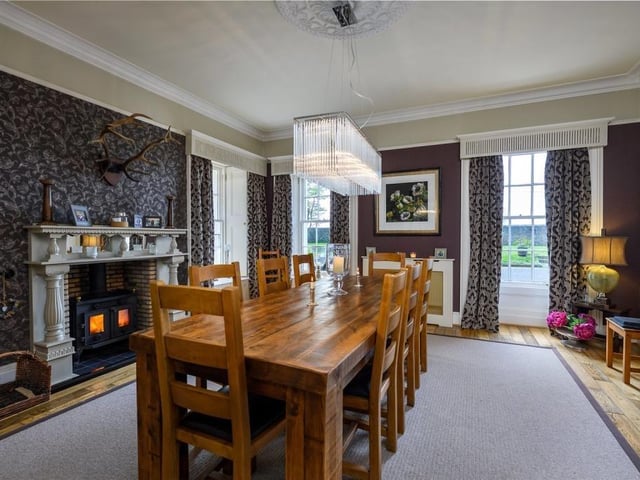 Dining Room with built-in bookshelves and cupboard, central fireplace with solid fuel stove and ornate pillared wooden mantel with inset mirrors.