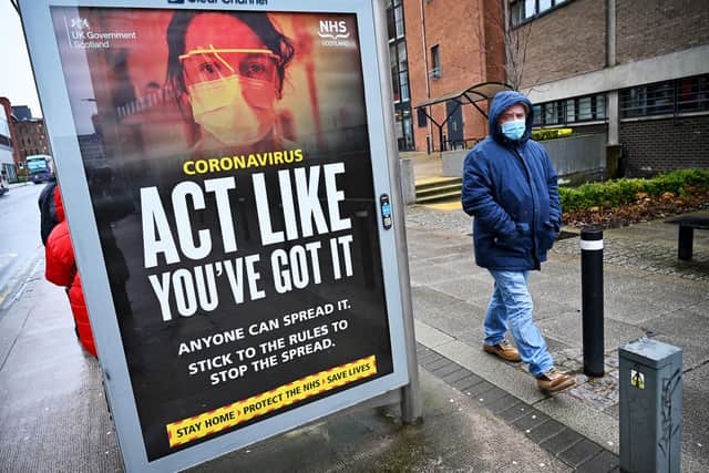 Members of the public walk past a government poster reminding people to socially distance and abide by the lockdown restrictions in the city centre on January 29, 2021 in Glasgow. Photo by Jeff J Mitchell/Getty Images