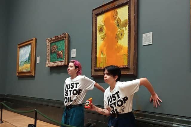 Activists with their hands glued to the wall under Vincent van Gogh's "Sunflowers" after throwing tomato soup on the painting at the National Gallery in central London (Photo by Handout / Just Stop Oil / AFP)