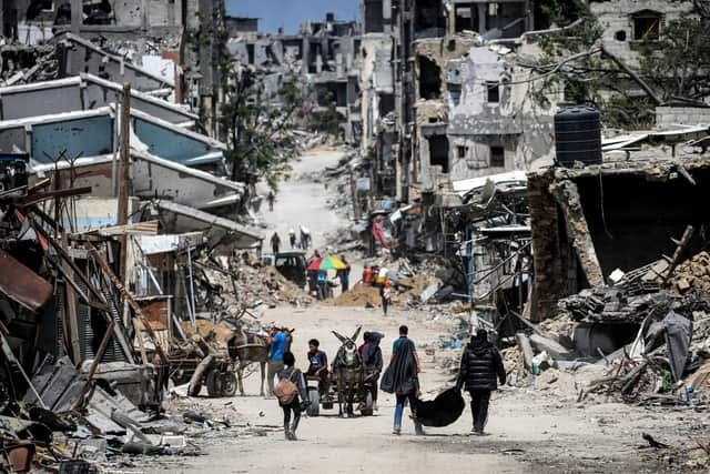 Gazans move along a street lined with destroyed buildings in Khan Yunis, southern Gaza Strip, earlier this week (Picture: AFP via Getty Images)