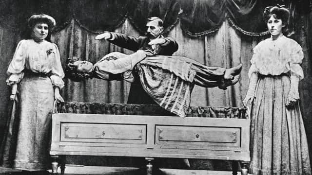 Conjuror Signor Martino performs a levitation on stage c.1900