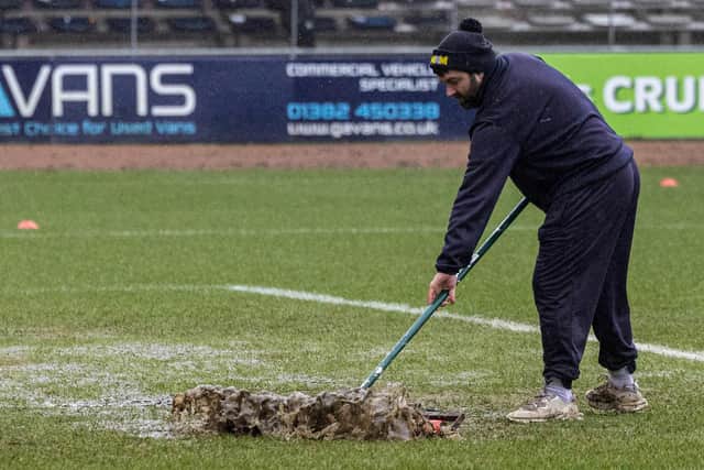 Dundee groundsman sweeps water off the pitch to no avail as the match against Aberdeen was postponed. (Photo by Mark Scates / SNS Group)