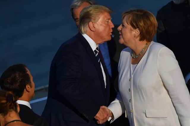 Donald Trump shakes hands as he kisses German Chancellor Angela Merkel during the G7 summit in France in 2019 (Picture: Nicholas Kamm/AFP via Getty Images)