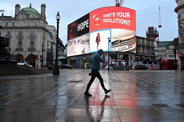 A pedestrian shelters from the rain as they walk across an almost deserted Piccadilly Circus as Britain enters a national lockdown in London. Picture: Justin Tallis/AFP via Getty Images
