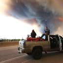 People wait at a road block as smoke rises from a wildfire near Fort McMurray, Alberta, Canada, on May 6, 2016 (Picture: Cole Burston/AFP via Getty Images)