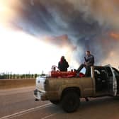 People wait at a road block as smoke rises from a wildfire near Fort McMurray, Alberta, Canada, on May 6, 2016 (Picture: Cole Burston/AFP via Getty Images)