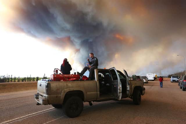 People wait at a road block as smoke rises from a wildfire near Fort McMurray, Alberta, Canada, on May 6, 2016 (Picture: Cole Burston/AFP via Getty Images)